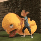 a boy is standing next to a giant yellow duck