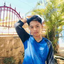 a young man in a blue shirt holds his hand to his head