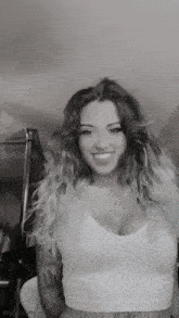 a black and white photo of a woman wearing a white crop top and smiling .