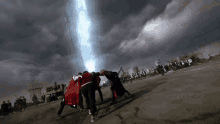 a group of people standing in a field with a light coming from the sky