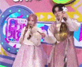 a man and a woman are standing on a stage with microphones .