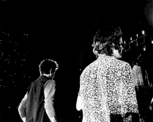 two men are standing next to each other in a black and white photo .
