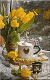 a cup of coffee with a heart on it sits next to a vase of yellow tulips and a good morning sign