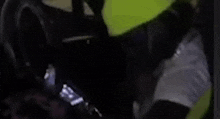 a man in a yellow helmet is holding a cell phone in his hand in a dark room .