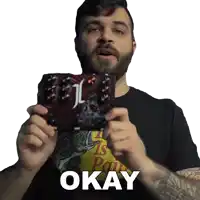 a man wearing a shirt that says okay is holding a guitar pedal
