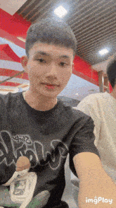 a young man taking a selfie with a black shirt that says ' draw ' on it