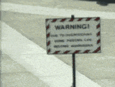 a warning sign is posted on the side of the road