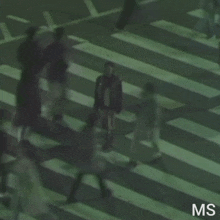 a blurred image of people crossing a street with the letters ms visible