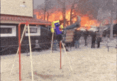 a person is sitting on a swing in front of a burning building