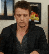 a man is sitting in front of a framed picture that says ' nirvana ' on it
