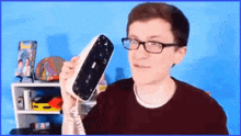 a young man wearing glasses is holding a broken telephone in his hand .