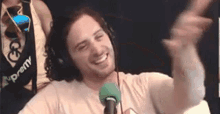 a man wearing headphones and a tie is sitting in front of a microphone and smiling .