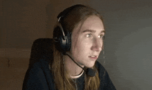 a woman with long hair wearing headphones and a microphone looks surprised