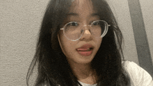 a girl wearing glasses and a white shirt is making a face