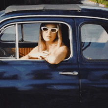 a woman wearing white sunglasses is sitting in a car