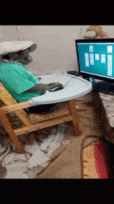 a monkey sits in a high chair in front of a computer monitor