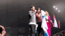 a group of people standing on a stage with a man holding a microphone