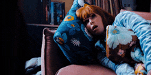 a woman laying on a couch with a blue pillow