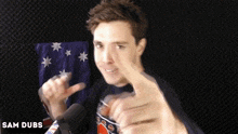 a man giving a thumbs up in front of a microphone with sam dubs written on the bottom left