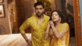 a man and a woman in yellow clothes are standing next to each other in a room .