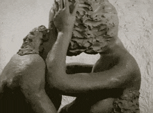 a black and white photo of a statue of a man and woman holding each other .
