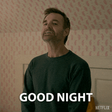 a man in a black sweater is smiling and says good night