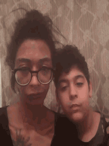 a woman wearing glasses is laying next to a boy wearing glasses