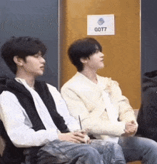 a couple of young men are sitting next to each other in a room .