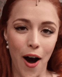 a close up of a woman 's face with her mouth open and pearl earrings