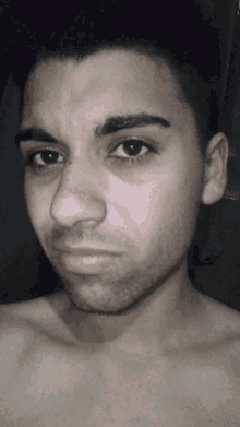 a man without a shirt looks at the camera