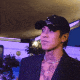 a man with a tattoo on his chest is wearing a hat and a necklace