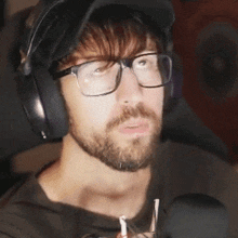 a man with glasses and headphones is sitting in a chair .