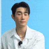 a man in a white shirt is sitting in front of a blue wall .