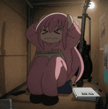a girl with pink hair is sitting in a dark room with a guitar