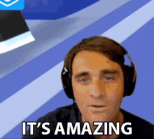 a man wearing headphones says it 's amazing in front of a blue background