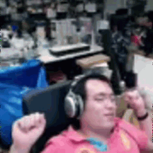 a man wearing headphones and a pink shirt is sitting in a chair