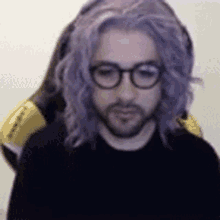a man with a beard and purple hair is wearing glasses and a wig .