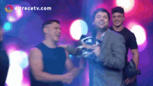 a group of men are standing in front of a screen with eltrecetv.com written on it