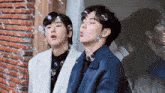 two men blowing soap bubbles in front of a window