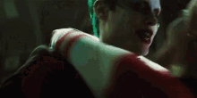 the joker and harley quinn are kissing in a dark room in suicide squad .
