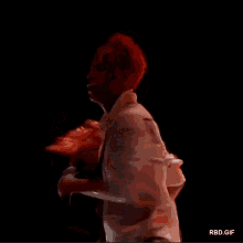 a man with red hair and a white shirt with the number 8 on the back is standing in a dark room .