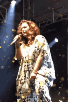 a woman is singing into a microphone on stage