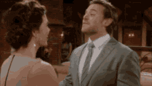 a man in a suit and tie is kissing a woman in a dress .