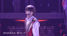 a young man in a red vest and white shirt is standing on a stage .