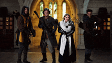 a group of people dressed in medieval costumes stand in a hallway