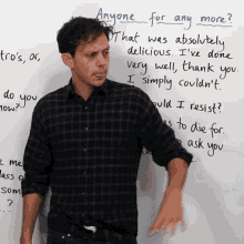 a man stands in front of a white board with the question " anyone for any more " on it