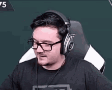 a man with glasses and headphones is sitting in a chair .