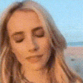 a woman with her eyes closed is standing on a beach .