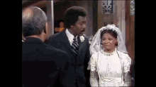 a man and a woman are standing next to each other in a wedding dress .