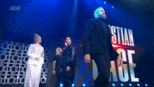 a group of people standing on a stage with the word aew on the bottom right